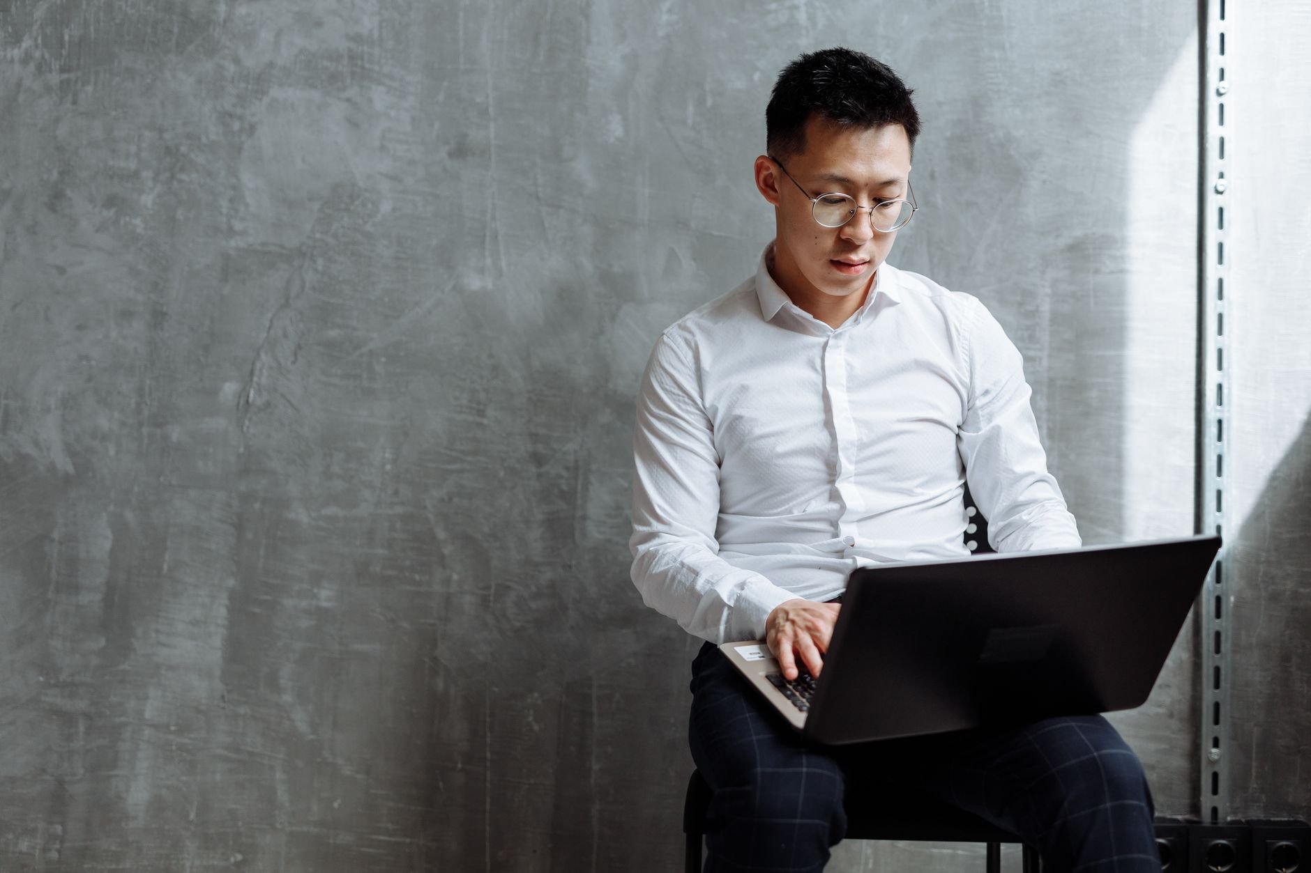 Person focused on laptop work in an indoor office setting.